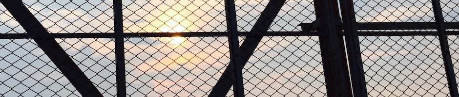 跨線橋の金網に差す夕日